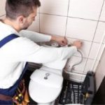 Plumber inspecting and repairing a toilet, emphasizing preventative maintenance for running toilet issues.