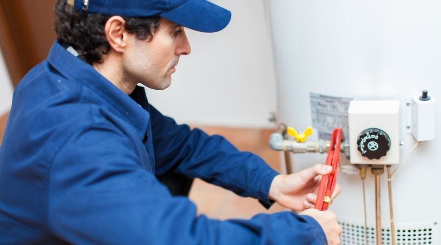 Plumber inspecting and repairing a water heater, emphasizing the importance of water heater maintenance and timely repairs.