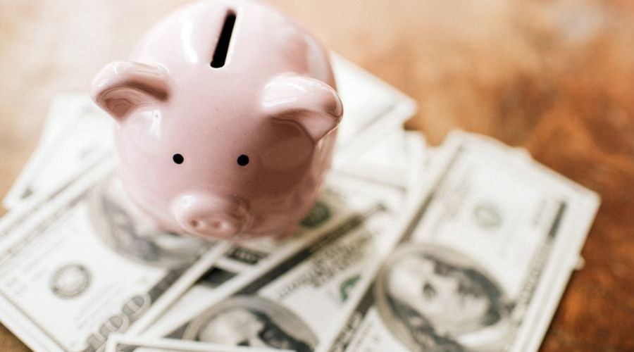Piggy bank on a pile of cash, symbolizing savings and financial tips for homeowners to reduce water costs.